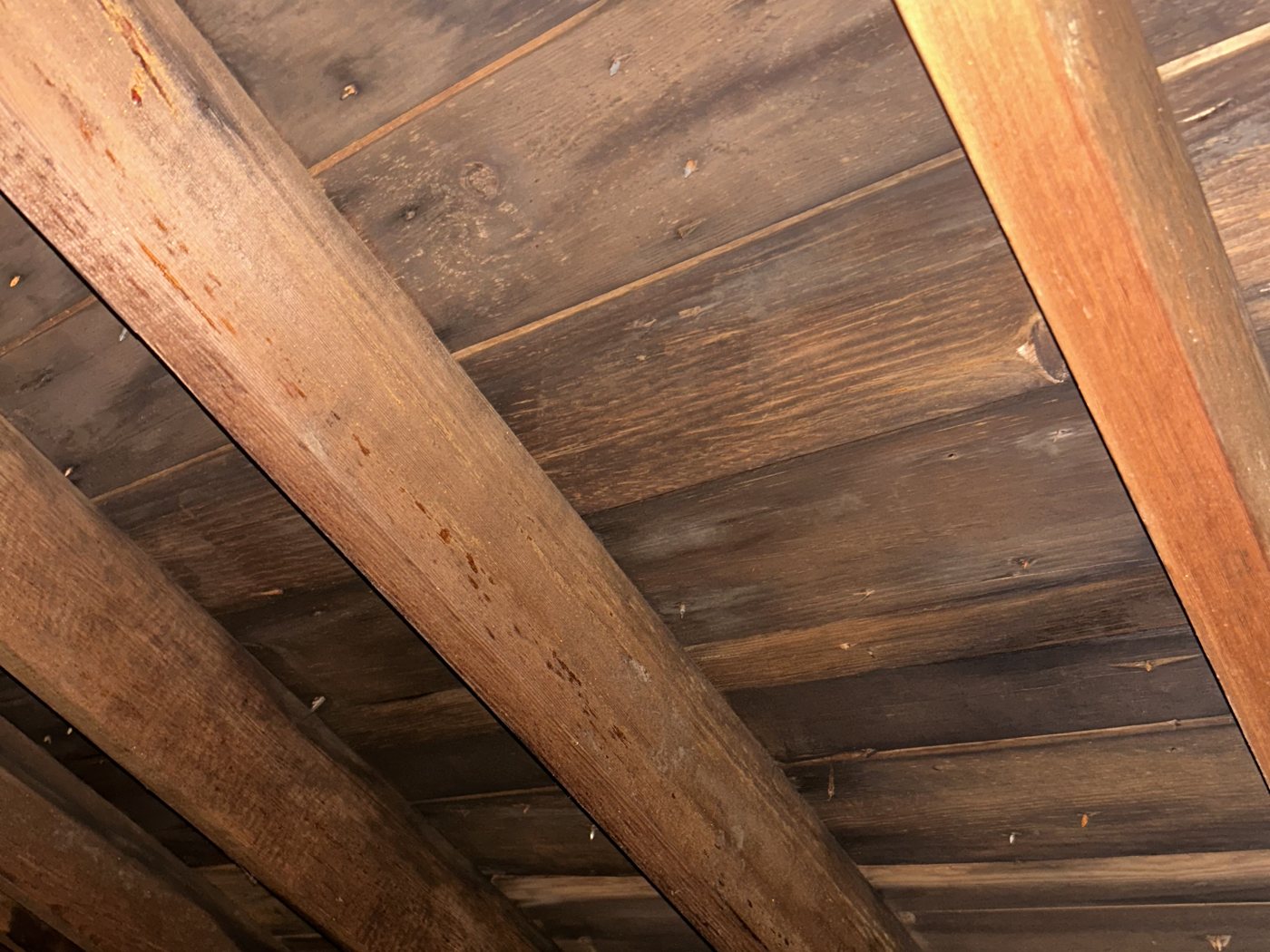 Attic view of tight tongue-and-groove plank roof decking with no visible gaps between boards